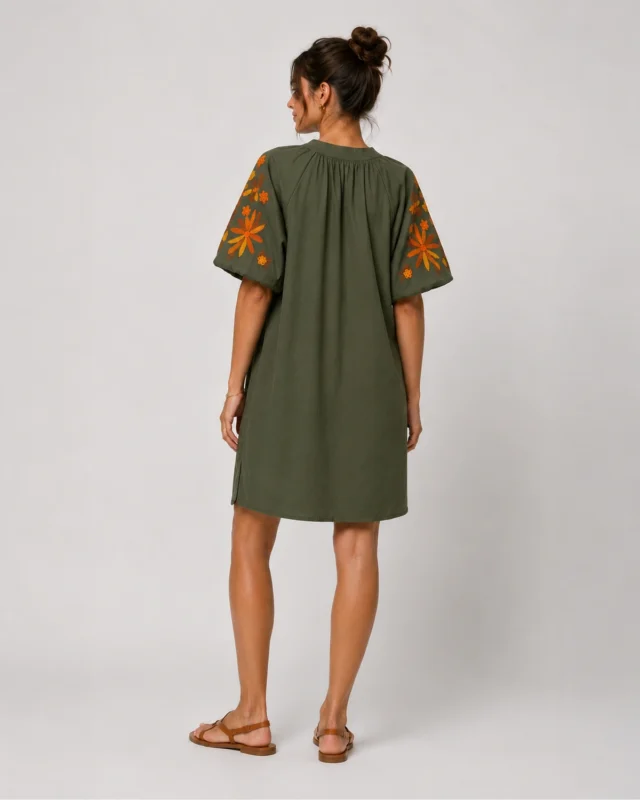 Robe kaki droite portée par un mannequin de dos, avec manches bouffantes brodées de fleurs orange, moutarde et marron.