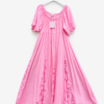 Robe longue rose fluide pour femme avec manches courtes bouffantes, empiècements en dentelle florale et étiquette visible, présentée sur cintre.