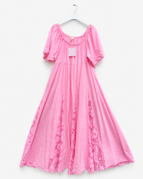 Robe longue rose fluide pour femme avec manches courtes bouffantes, empiècements en dentelle florale et étiquette visible, présentée sur cintre.